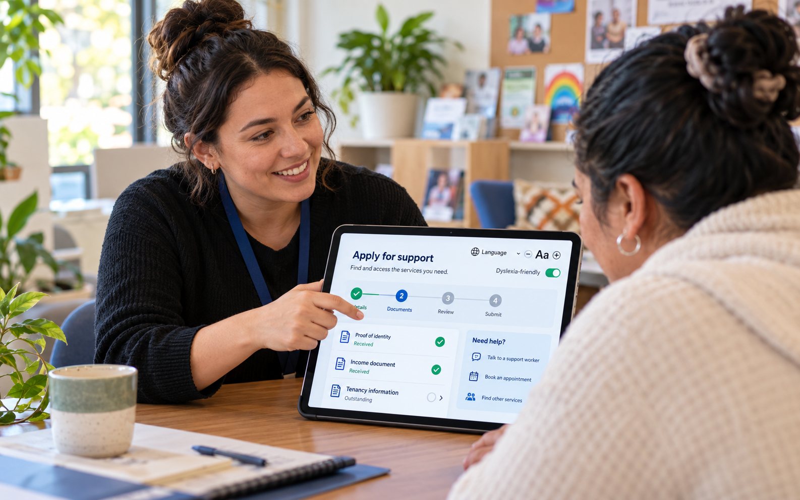 A support worker helping a client apply for services on a tablet app with accessibility settings